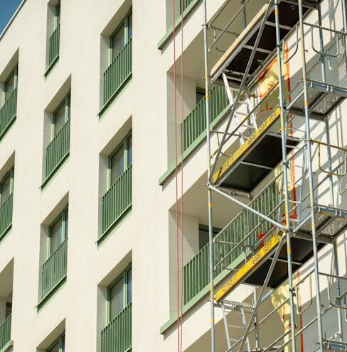A contemporary apartment building with scaffolding on a sunny day in Wrocław, Poland.